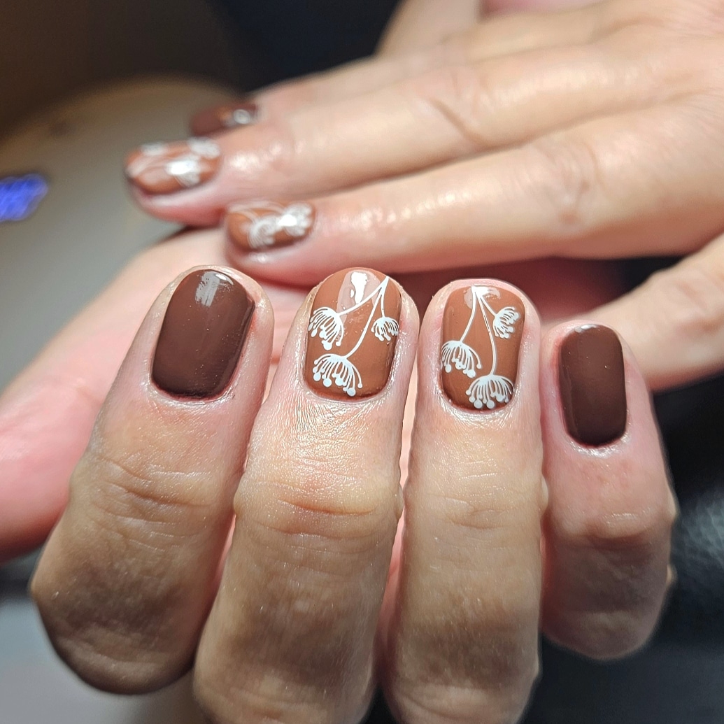 Bruine nagels met witte, getekende bloemetjes